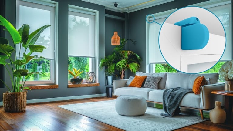 Modernes Wohnzimmer mit grauen Wänden, großen Fenstern mit Rollos, grünen Pflanzen, einem grauen Sofa, orangefarbenen Kissen und einer runden Ottomane.